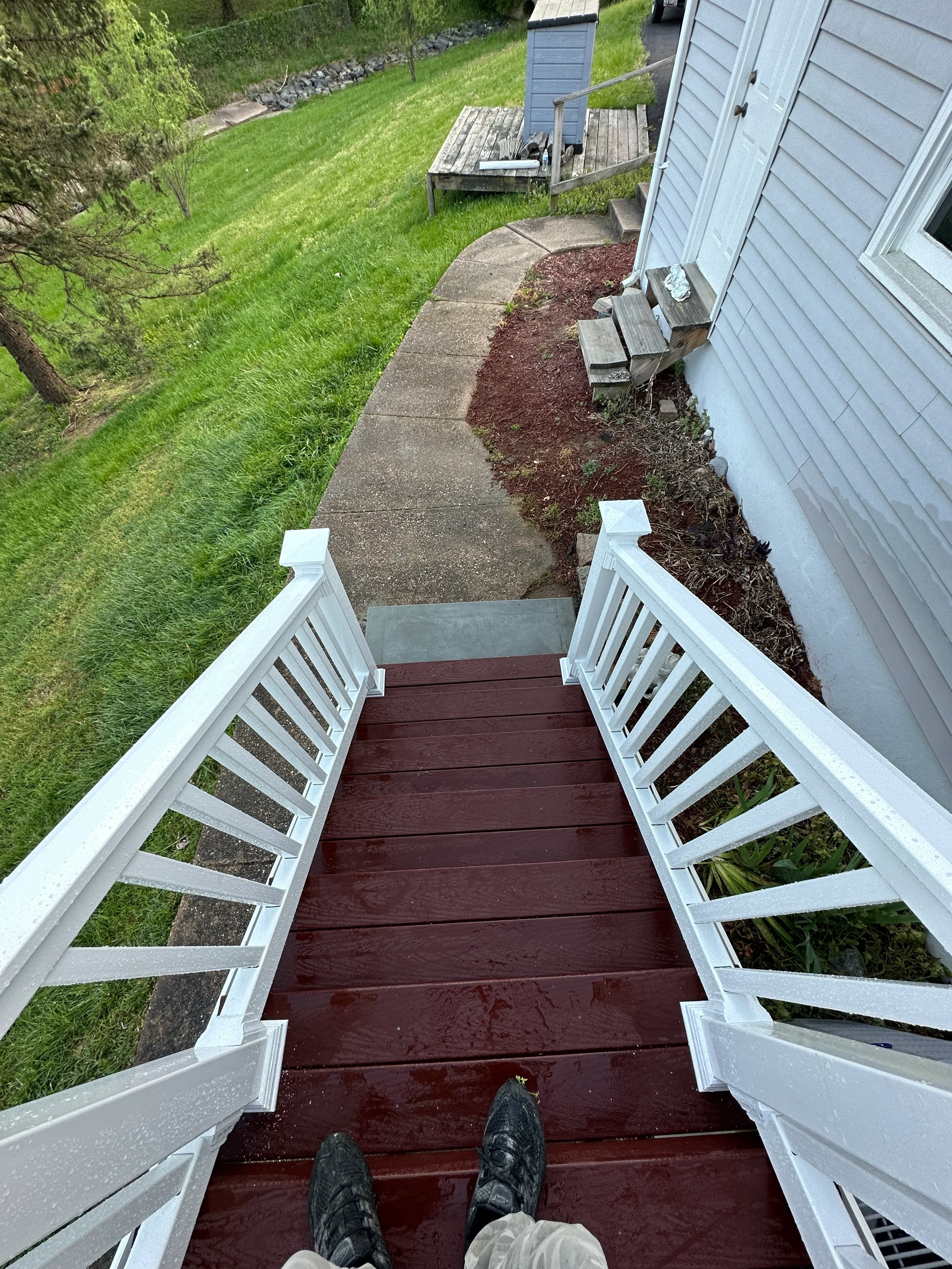 Dark stained deck with white railings overlooking manicured lawn and landscaping