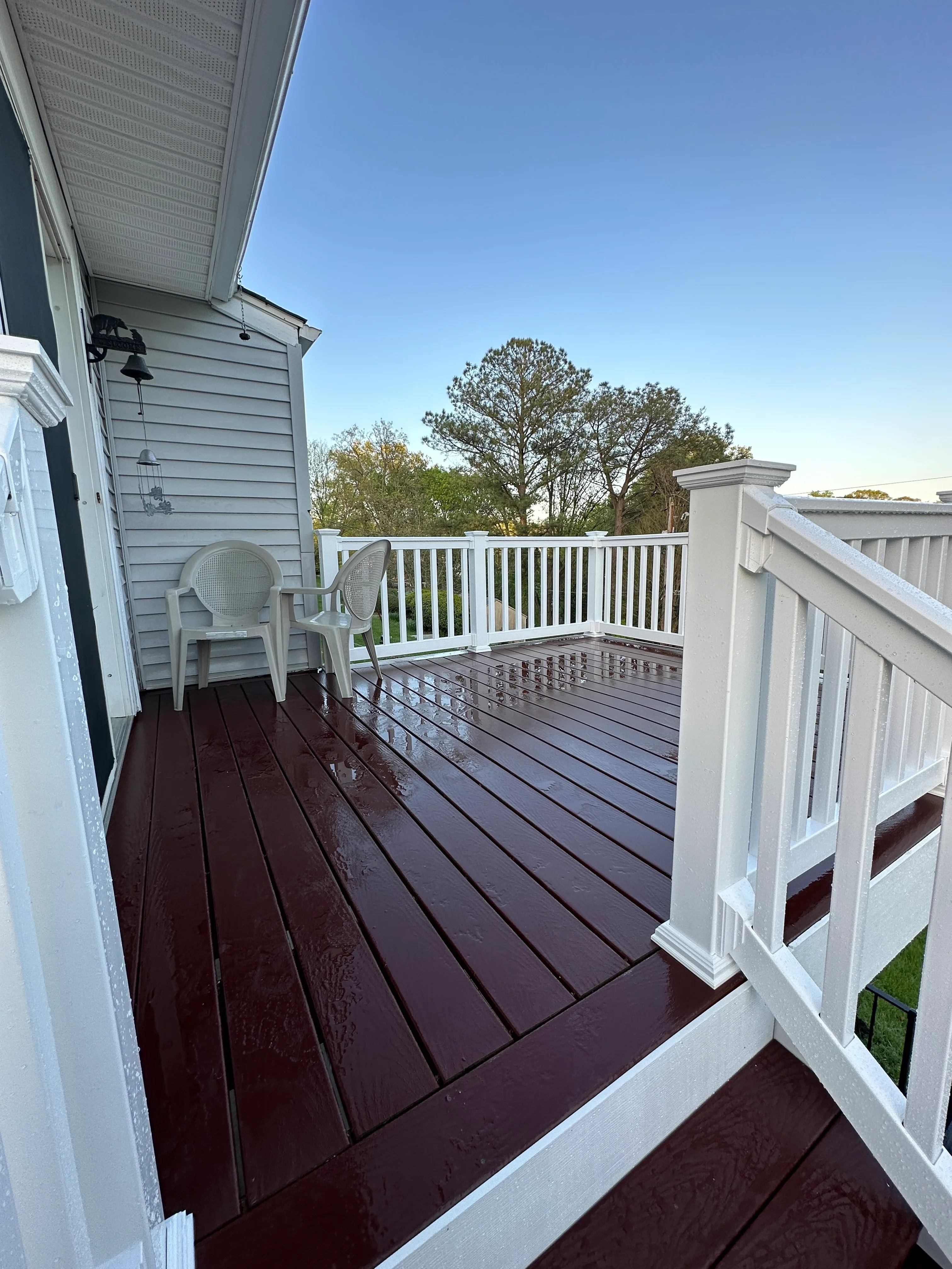 Dark composite deck with white vinyl railings and post caps overlooking trees
